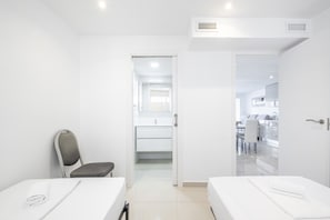 Ein Hotelzimmer mit Bett, Stuhl, Schreibtisch und einem durch eine offene Tür einsehbaren Badezimmer.