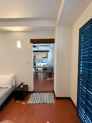 Een modern interieur met een bed, nachtkastje en uitzicht op een keuken.