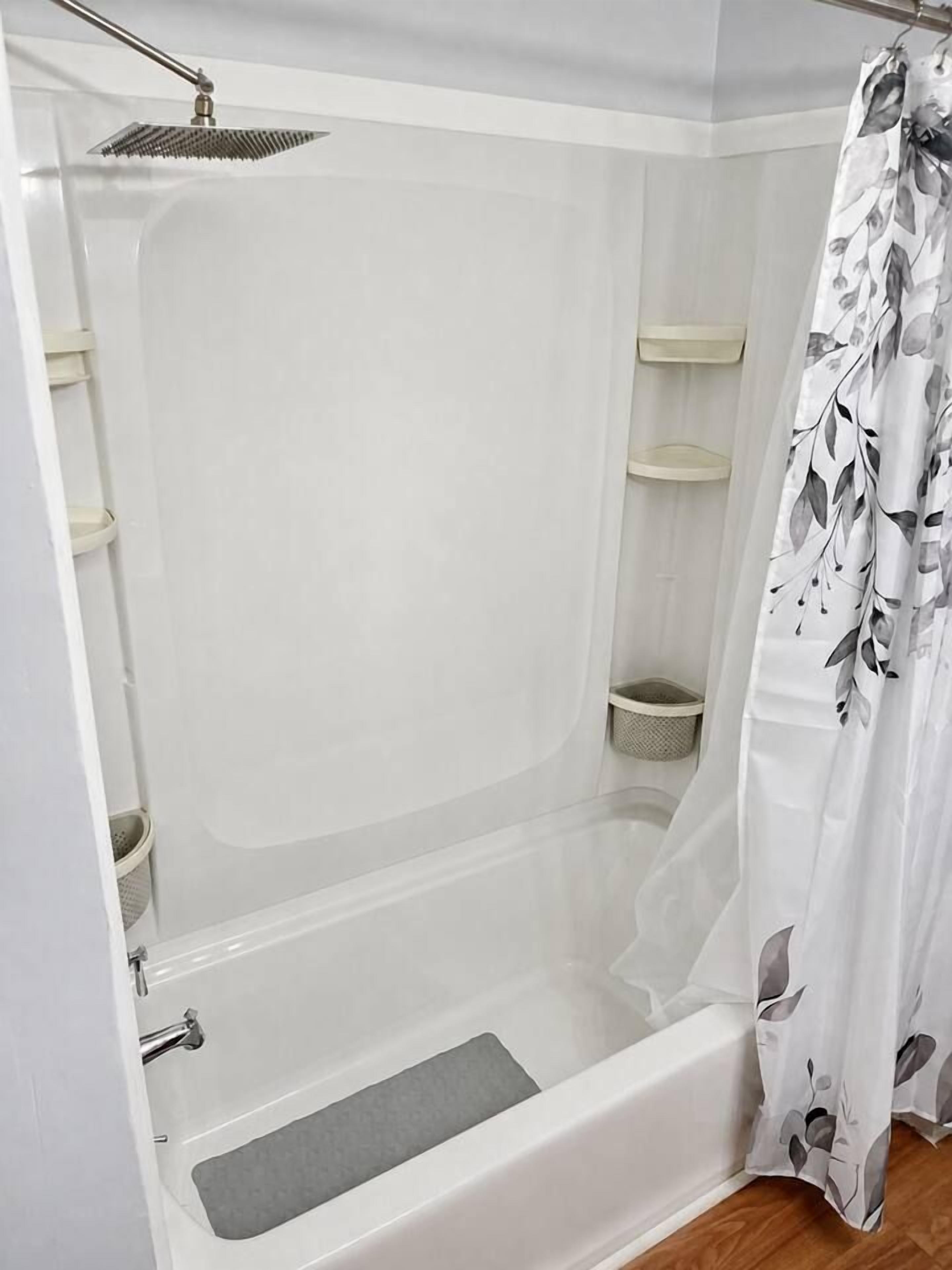A walk-in shower with a glass door, a showerhead, and a shower curtain.