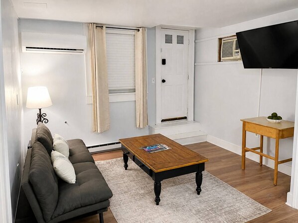 Een woonkamer met een bank, salontafel en een televisie op een dressoir.