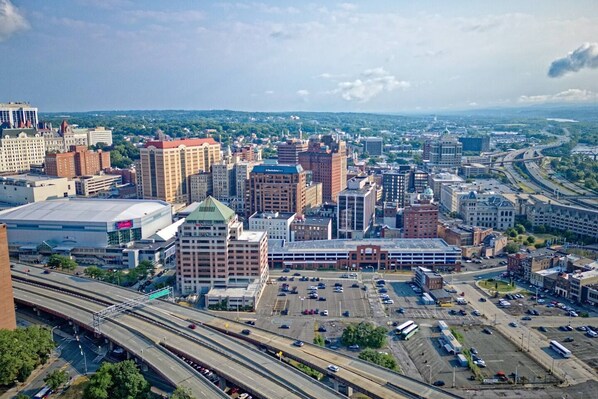 A cityscape with multiple high-rise buildings, a large parking lot, and a highway.