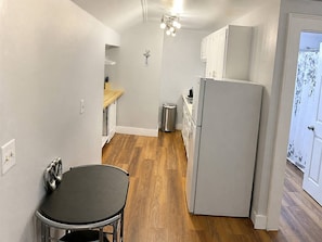 A compact kitchen with a refrigerator, a sink, and a wooden floor.