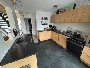 Una cocina moderna con encimera negra, armarios de madera y lavavajillas negro.