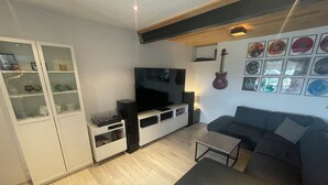 Ein modernes Wohnzimmer mit Fernseher, einer Couch, einem Couchtisch und einer Vitrine.