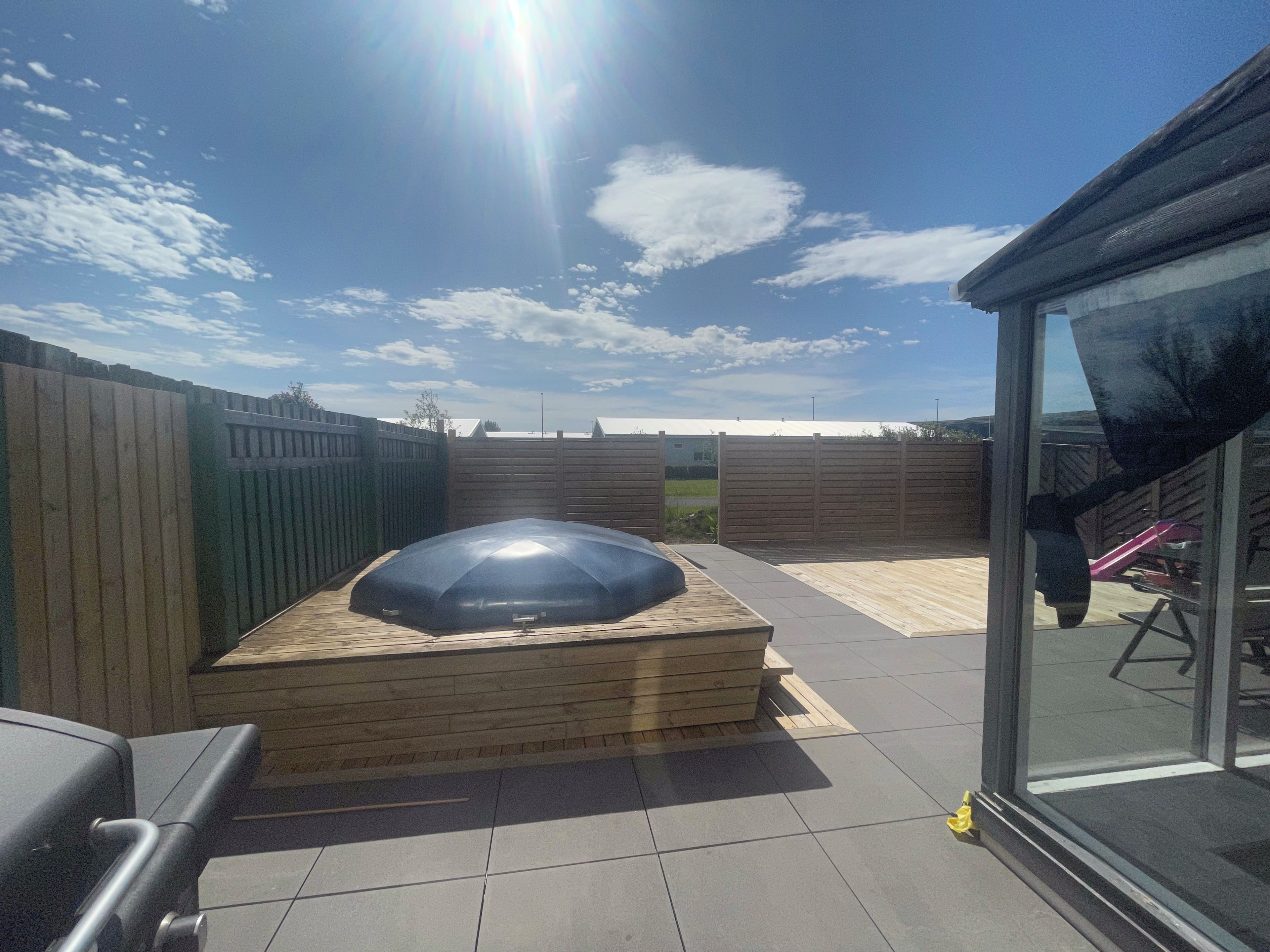 Eine Terrasse mit Grill, einem überdachten Sitzbereich und einer Glastür zum Innenraum.