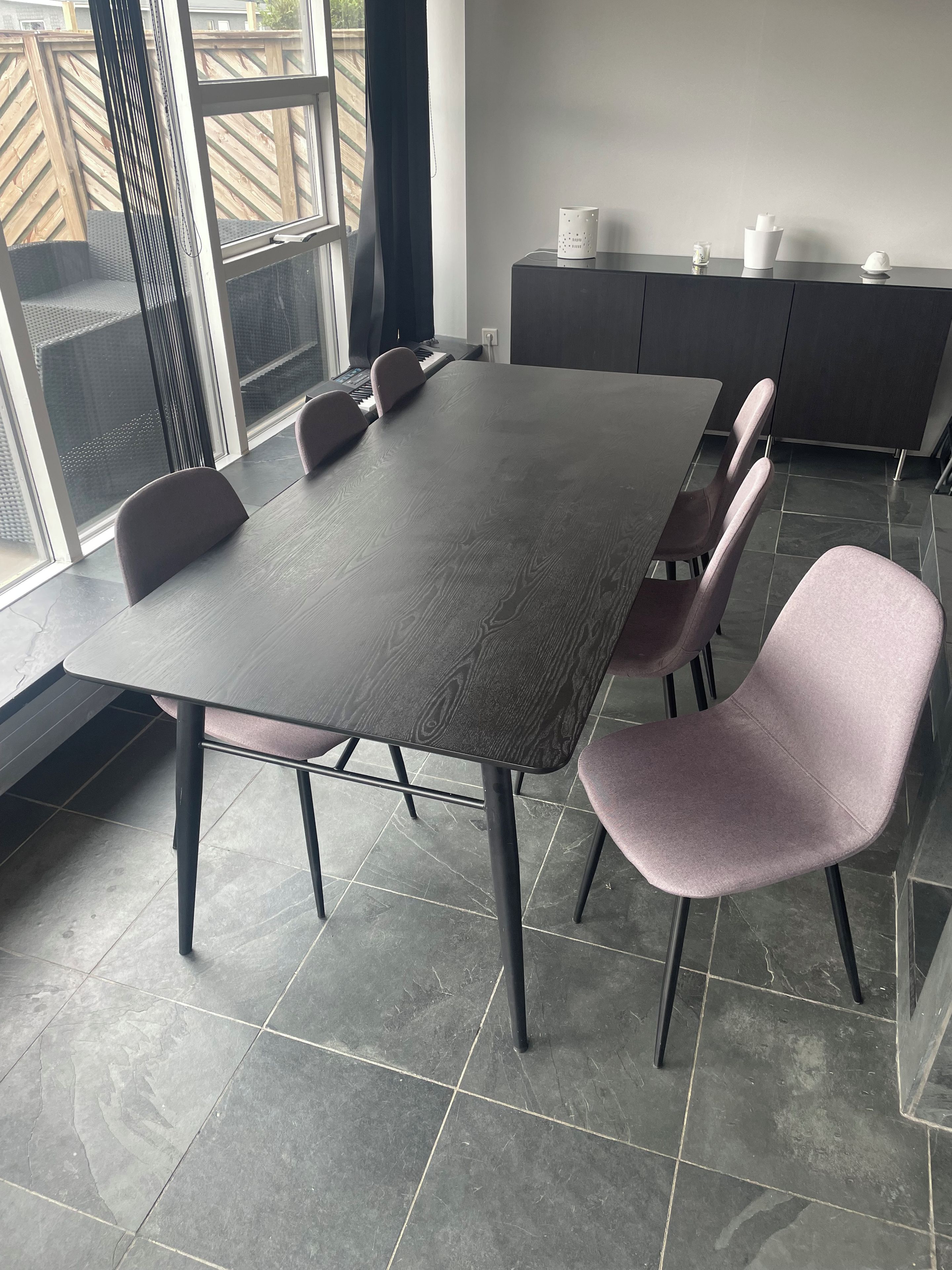 Une salle de conférence avec une grande table, des chaises, un clavier et un meuble sur lequel sont posés divers objets.