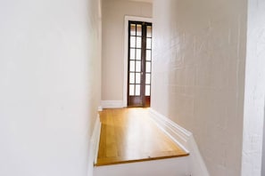 Un couloir étroit avec un plancher en bois et des murs blancs.