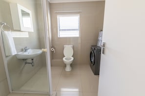 Une petite salle de bain comprenant un lavabo, des toilettes et un lave-linge.