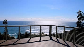 A wooden deck with a metal railing overlooking a coastal view.