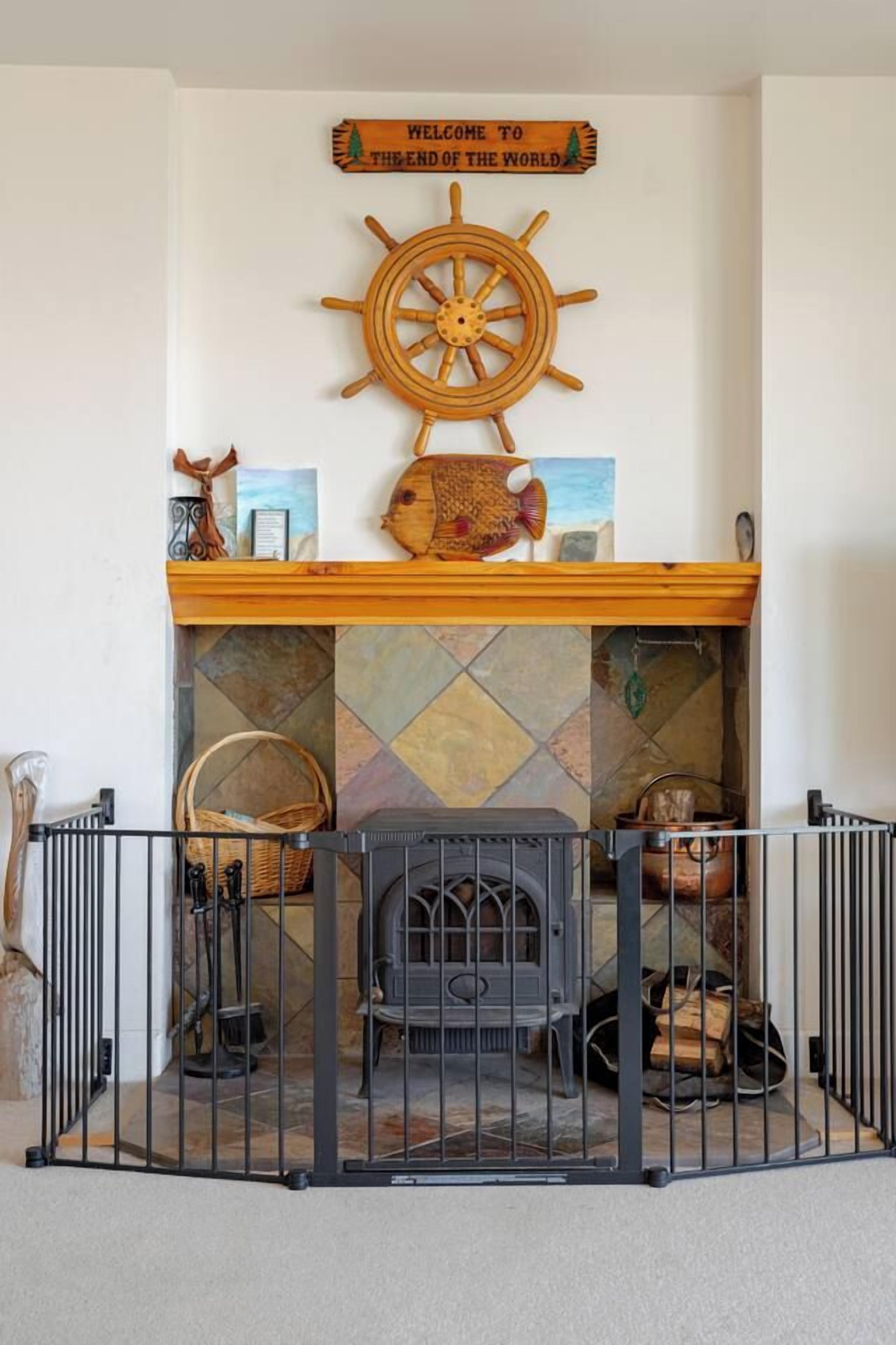 A fireplace with a decorative sign above it, a wooden shelf with various items, and a metal railing in front.