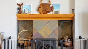 A fireplace with a decorative sign above it, a wooden shelf with various items, and a metal railing in front.
