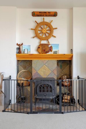 A fireplace with a decorative sign above it, a wooden shelf with various items, and a metal railing in front.