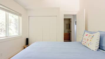 A bedroom with a bed, a wardrobe, and a view of a kitchen through an open door.