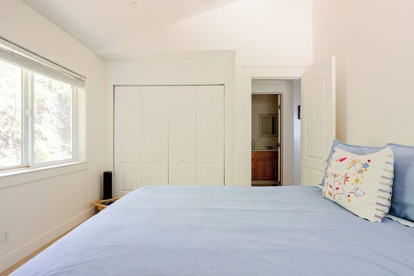 A bedroom with a bed, a wardrobe, and a view of a kitchen through an open door.