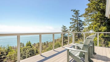 A wooden deck with a railing overlooking a body of water and trees.