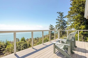 A wooden deck with a railing overlooking a body of water and trees.