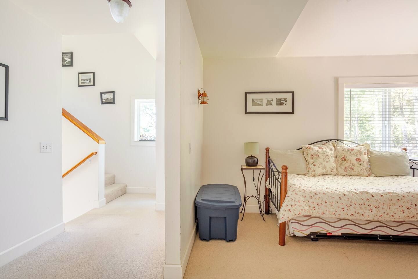 A bedroom with a bed, a nightstand, a lamp, and a window.