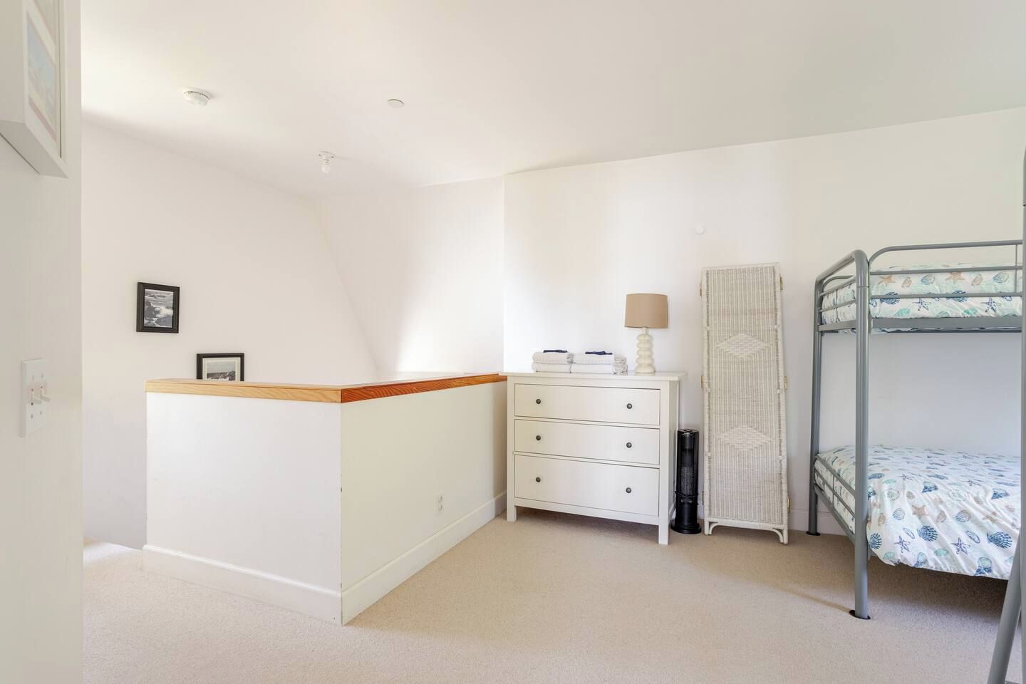 A bedroom with a bunk bed, a dresser, a lamp, and a framed picture on the wall.