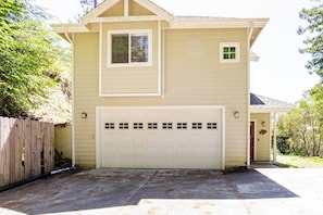 A two-story house with a garage, a small porch, and a wooden fence. - Serene Coastal Retreat Clark's Cove - Holiday Home (Jenner)