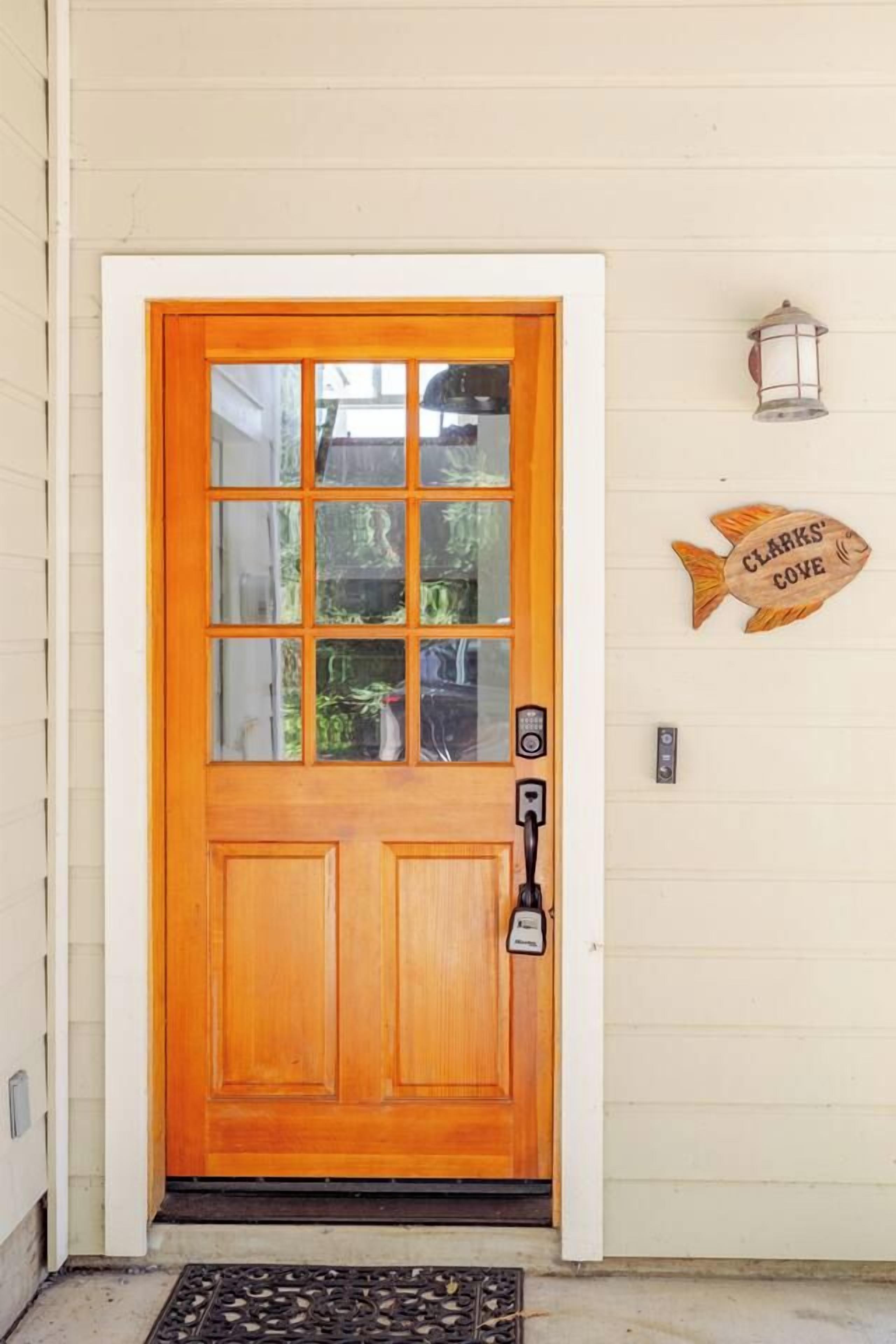 Puerta de madera con un panel de vidrio, un picaporte y una lámpara de pared.