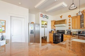 Una cocina con refrigerador de acero inoxidable, horno doble, armarios de madera y encimera de granito.