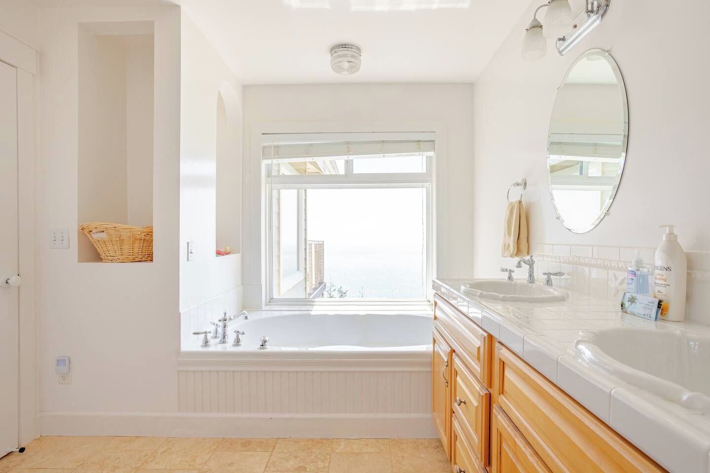 Un baño moderno con una bañera independiente, un espejo grande y una ventana que ofrece vistas a la ciudad.
