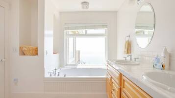 Un baño moderno con una bañera independiente, un espejo grande y una ventana que ofrece vistas a la ciudad.