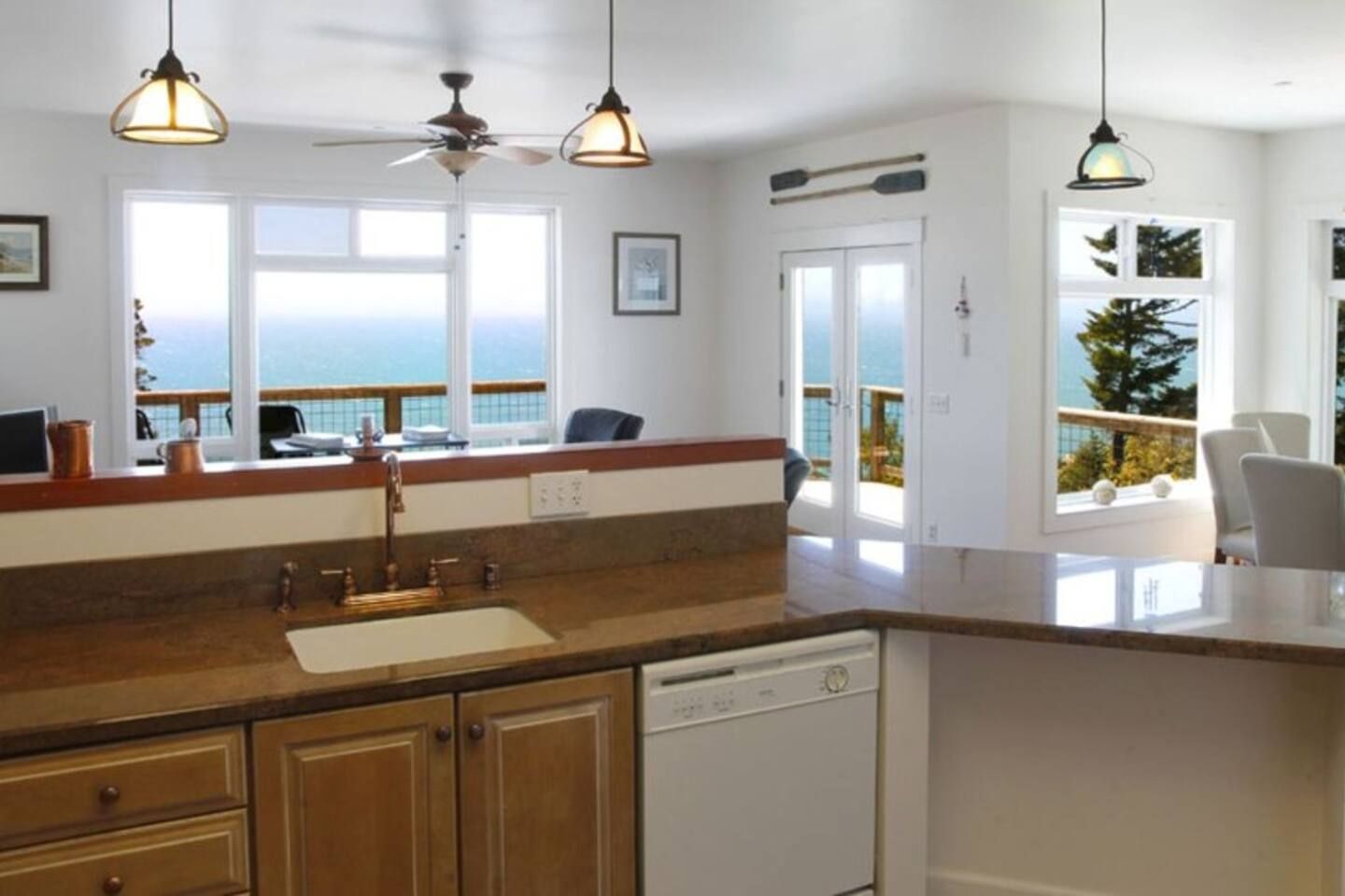 A kitchen with a view of the sea, a ceiling fan, and pendant lights.