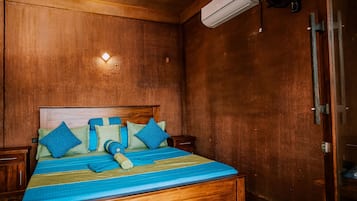 A wooden-paneled room with a bed, a wall-mounted air conditioner, and a small table.