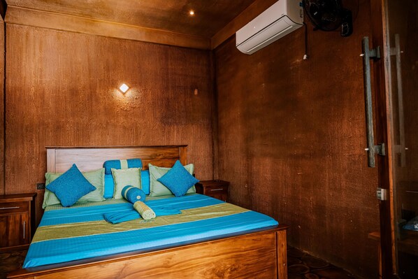 A wooden-paneled room with a bed, a wall-mounted air conditioner, and a small table.