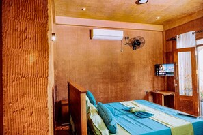 A room with a bed, a wall-mounted air conditioner, a television, and a window with curtains.
