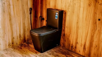 Un espacio pequeño y cerrado con interior de madera, un objeto negro pequeño con tapa y una etiqueta de contador de agua.