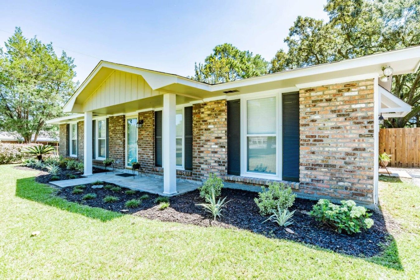 A modern two-story house with a brick facade, a covered porch, and a landscaped front yard.