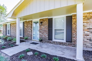 A two-story house with a brick facade, white trim, and a covered porch with potted plants. - Johnson Oaks (Mobile)