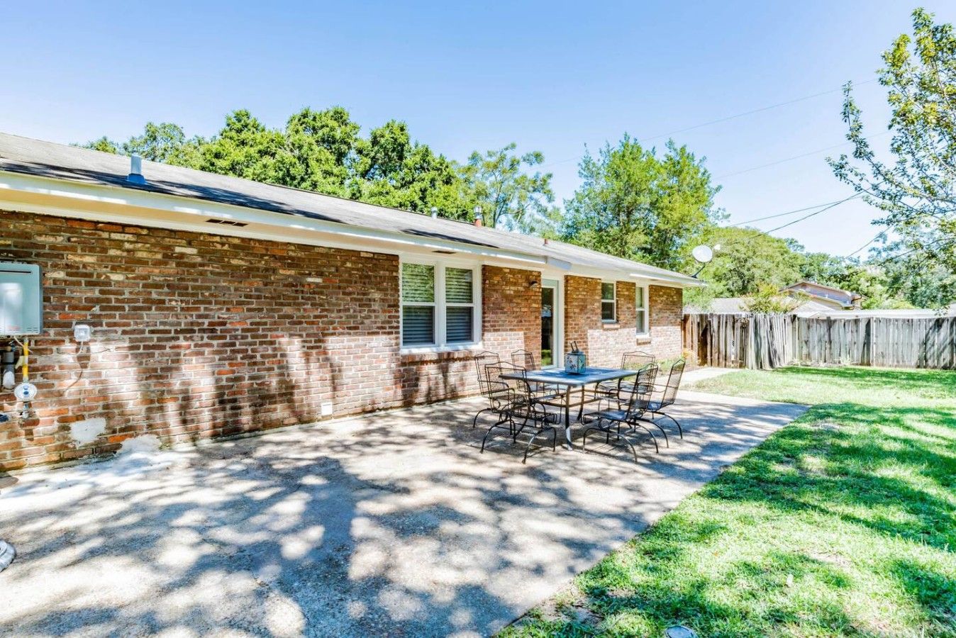 A single-story brick house with a patio area featuring a table and chairs.