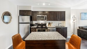 A modern kitchen with dark cabinets, stainless steel appliances, and a granite countertop. - StayToronto - Fort York Prime Suites (Toronto)