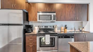 Una cocina moderna con electrodomésticos de acero inoxidable, armarios de madera y encimera de granito.