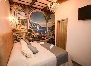 Un dormitorio con una cama, una puerta de madera, una araña y un mural de una escena costera.