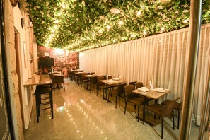 Un restaurante con una barra alargada, varias mesas y sillas.