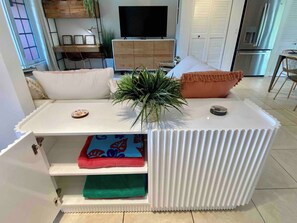 Ett modernt vardagsrum med en vit möbel för underhållningssystemet, en platt-TV och en matplats med ett bord och stolar.