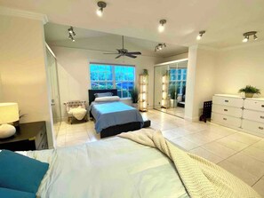 Ein modernes Schlafzimmer mit einem Bett, Nachttischen, einem Deckenventilator und einem großen Fenster.