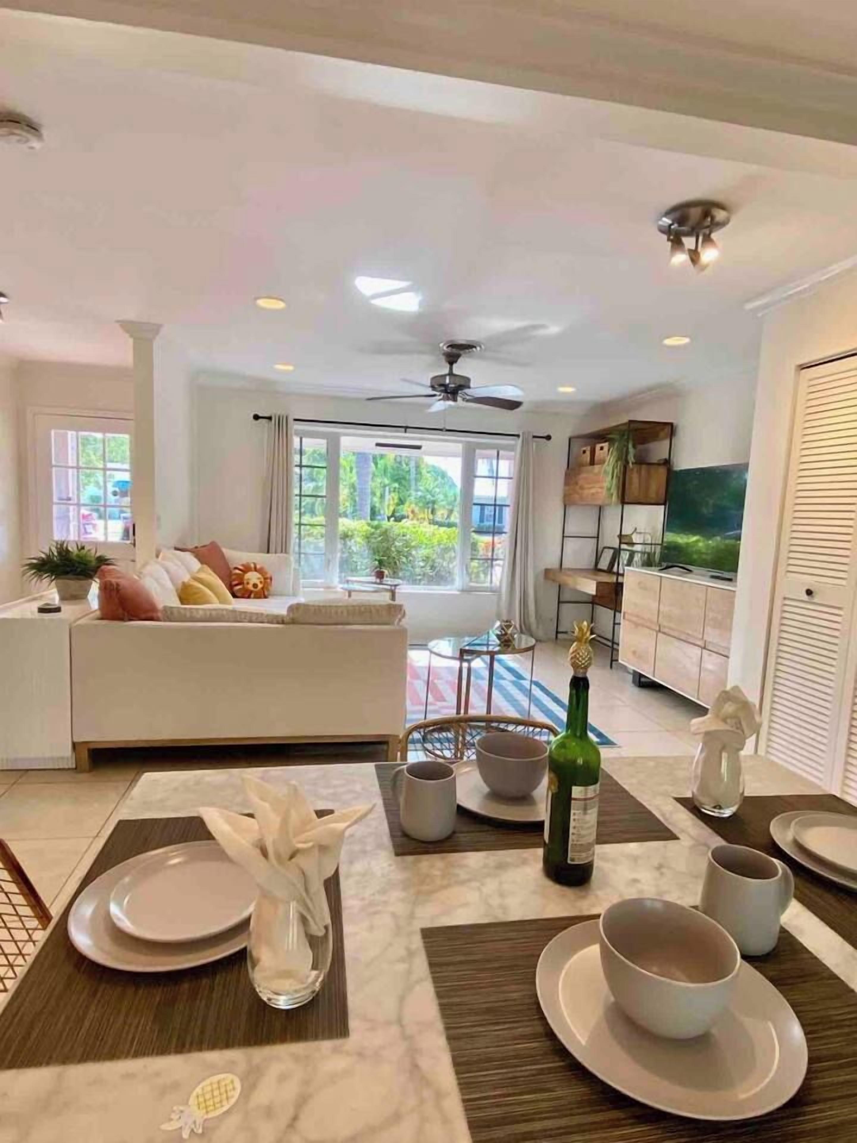 A modern living room with a sofa, dining table set with plates and cups, and a television in the background.