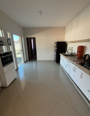A spacious kitchen with white cabinets, a black refrigerator, and a coffee machine. - Country estate in Esmeraldas near Belo Horizonte (Esmeraldas)