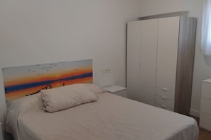 Ein Schlafzimmer mit einem Bett, einem Kleiderschrank und einem Bild an der Wand.