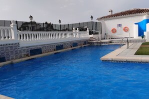 Ein Schwimmbecken mit weißem Zaun, einem Rettungsring und einem Gebäude mit blauer Tür.