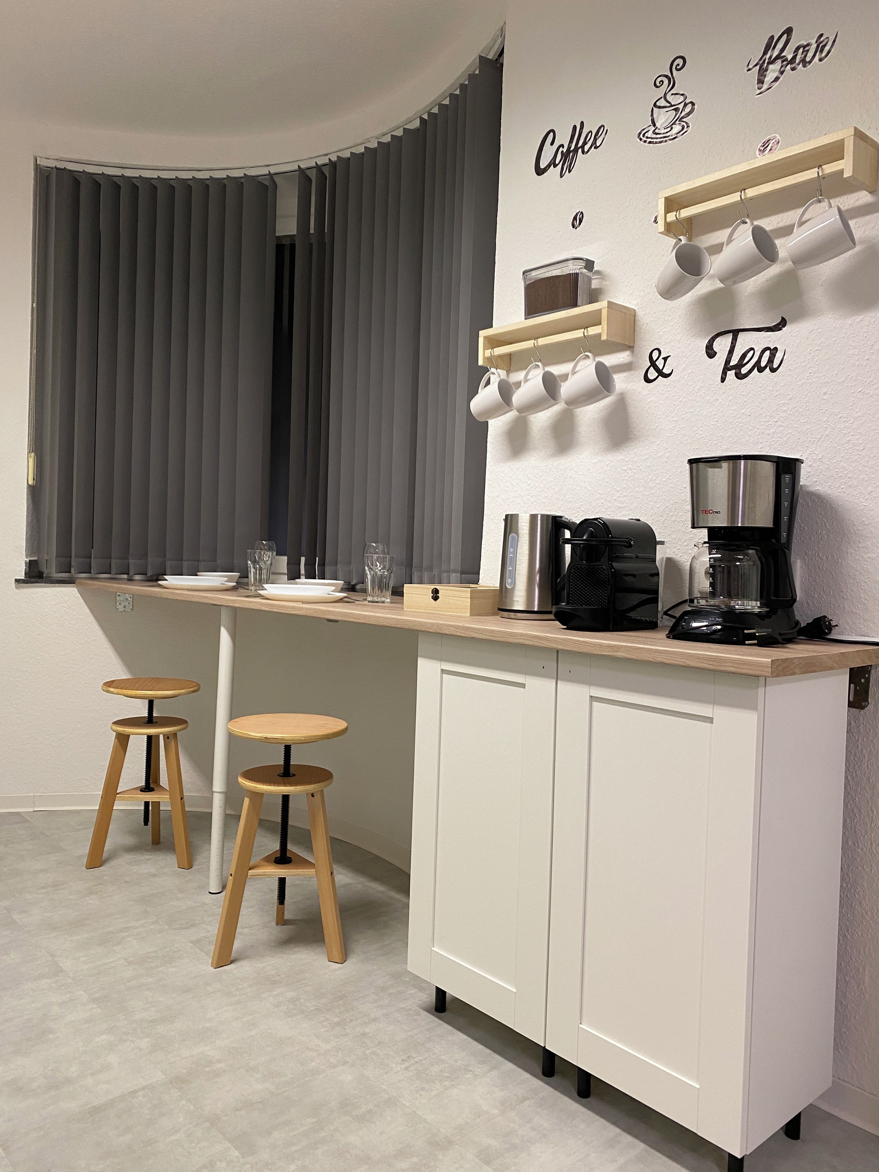 Eine moderne Küche mit Barbereich, einer Kaffeemaschine und zwei Barhocker.