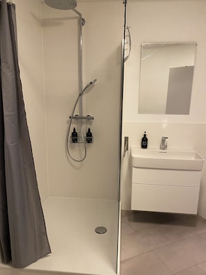 Ein modernes Badezimmer mit Dusche, Waschbecken und Spiegel.