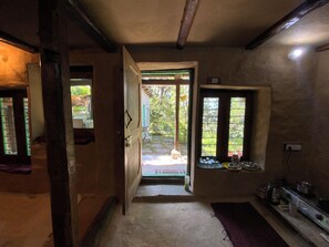 A narrow hallway leading to a door with a view of an outdoor area. - Tranquil 1-bedroom Mud House in charming Bashisht perfect for getaway (Bashisht)