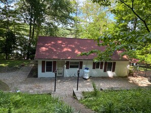 A small, single-story house with a red roof and white walls, surrounded by lush greenery and trees. - Cozy Family-Friendly 2-Bedroom Lakeview Retreat in Waverly, OH with AC (Waverly)