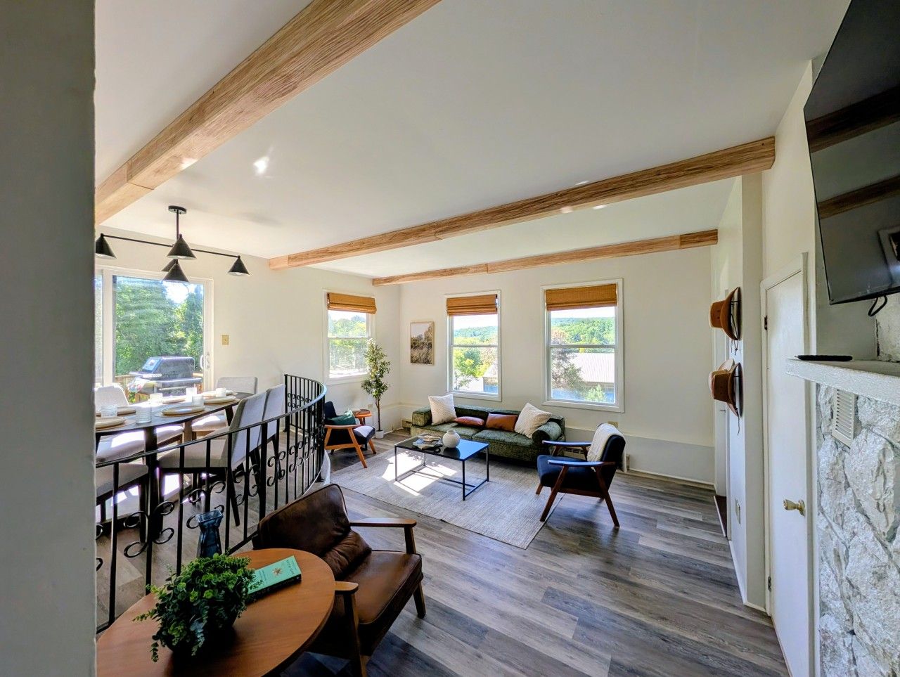 A spacious living area with a dining table, seating arrangements, and large windows providing natural light.